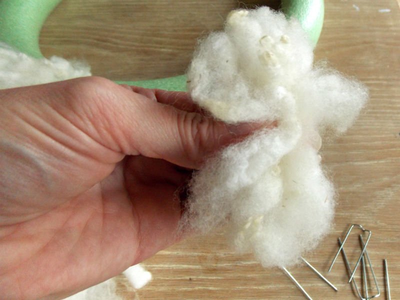 Attach the sheep wool to the foam wreath form with the floral pins