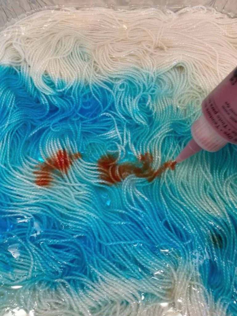 image of orange dye added to blue yarn