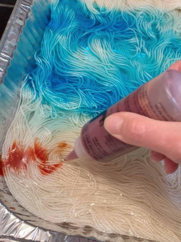 image of orange dye painted on white yarn